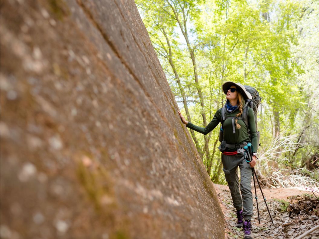 A woman next to a rock with abckpacking gear on
